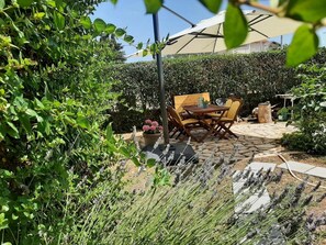 A patio with a table and chairs, surrounded by lush greenery and lavender plants. - Apartments Borna - One Bedroom Apartment with Terrace (Drage)