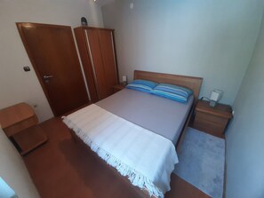 A bedroom with a bed, a nightstand, a wardrobe, and a small table.