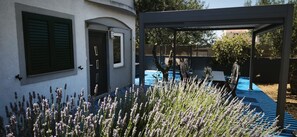 A pool area with a pergola, a door, and lavender plants.