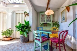 A dining area with a table and chairs, potted plants, and a hanging light fixture.