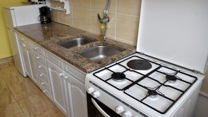A kitchen with a gas stove, two sinks, and a coffee maker. - Studio apartment Eva- Old City Center (Zadar)