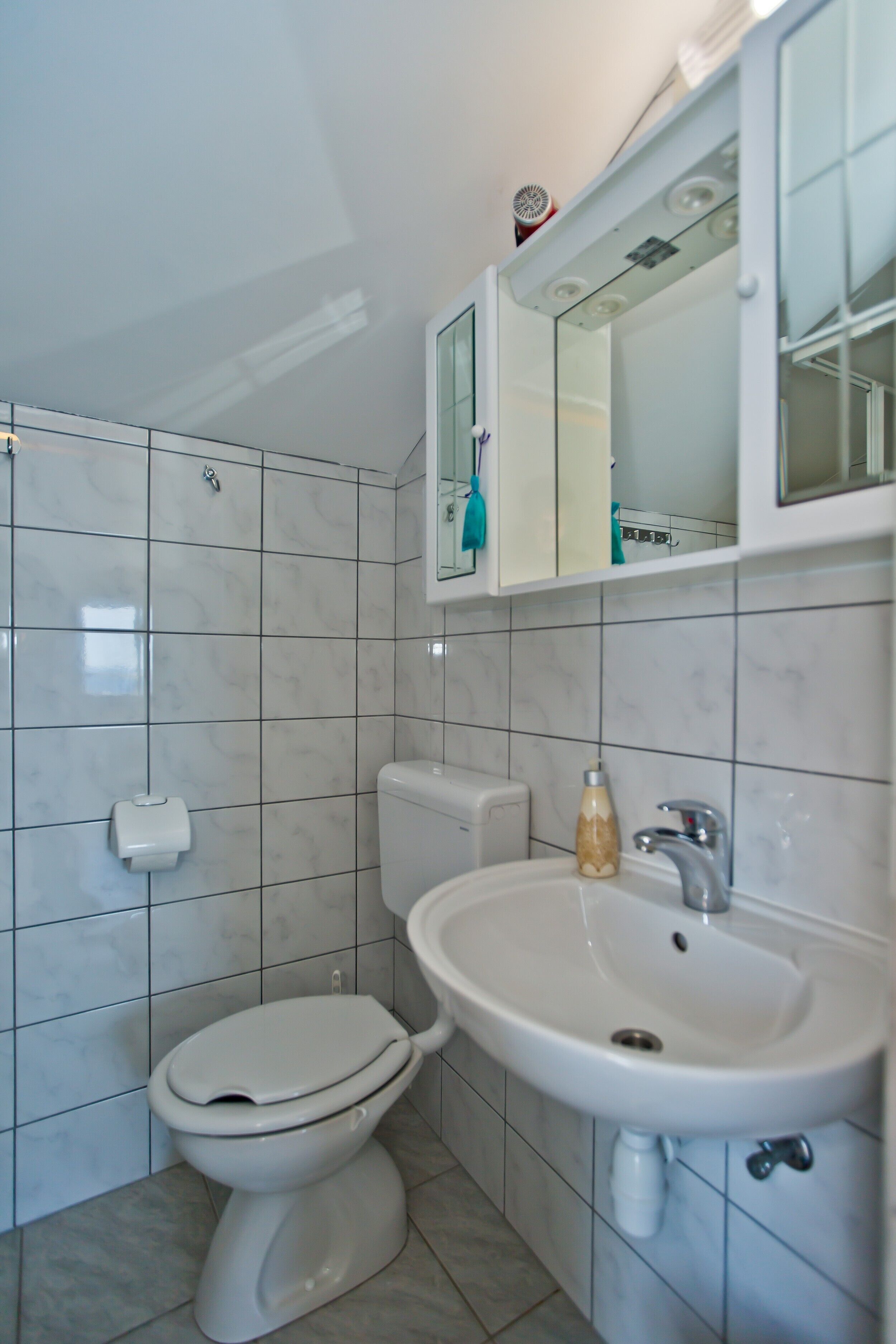 A bathroom with a toilet, sink, and mirror.