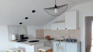 A compact kitchen with a central island, white cabinetry, and a hanging light fixture.
