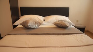 Un lit bien fait, avec une tête de lit sombre, deux oreillers et une couverture à rayures.
