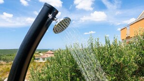 A showerhead with water spraying over a garden.