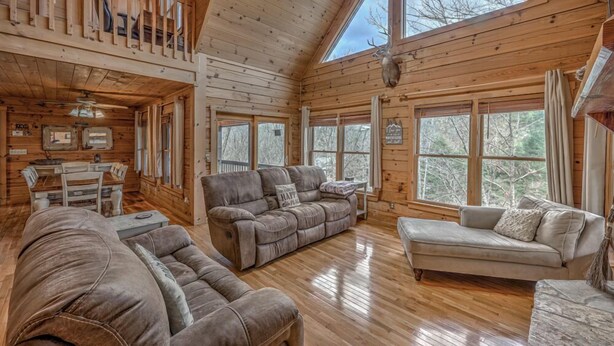 A cozy cabin interior with a wooden interior, a dining area, and a large window offering a view of the outdoors.