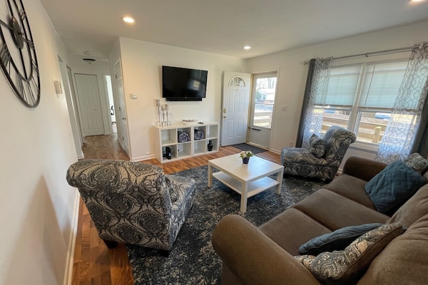 Front door opens up to living room that includes a smart tv, two chairs, couch