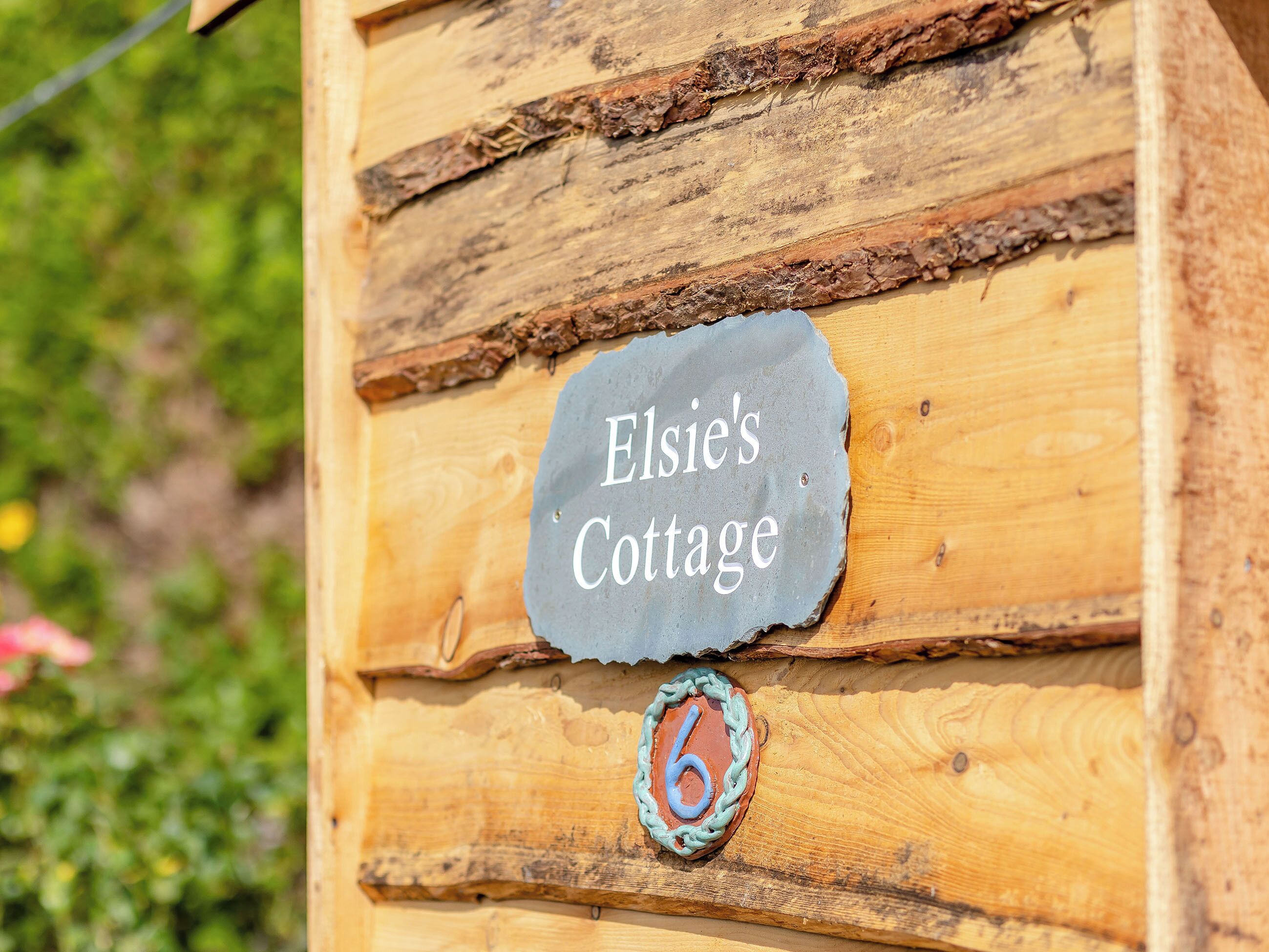 En liten stuga byggd av trä, med en skylt som visar texten ”Elsies stuga” och siffran ”6” under.