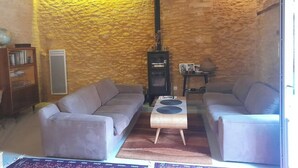 Una sala de estar acogedora con una pared de piedra, dos sofás, una mesita y una chimenea.