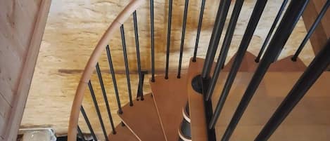 A wooden spiral staircase with black metal railings and a wooden handrail.