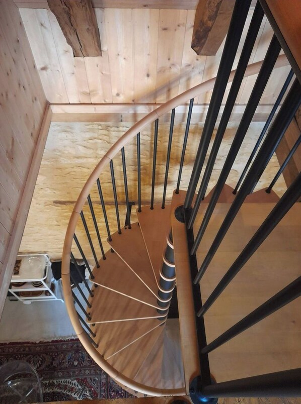 A wooden spiral staircase with black metal railings and a wooden handrail. - Restful, warm house in Périgord Noir. (Thonac)