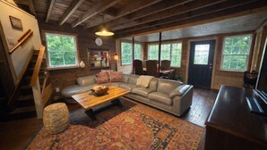 Un salon chaleureux avec un plafond en bois, un canapé en cuir, une table basse et un tapis à motifs.
