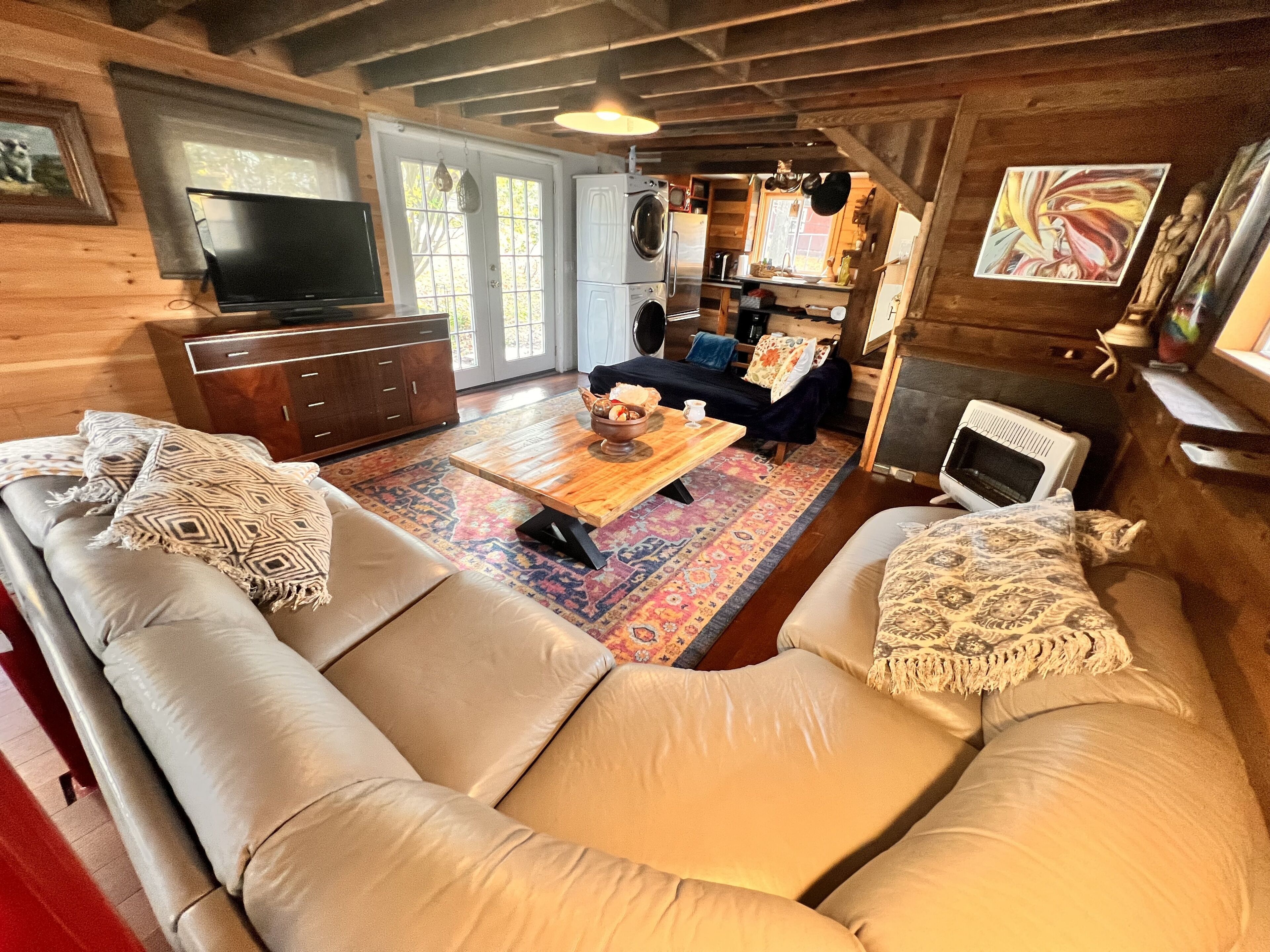 A cozy cabin interior with a sofa, a coffee table, a television, and a kitchen area.