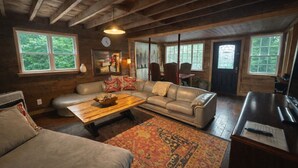 Un intérieur de chalet chaleureux et accueillant, avec un canapé, une table basse et un coin repas.