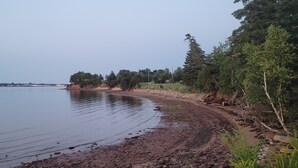 A calm lake with a rocky shoreline and trees. - Quaint 2 bedroom water view cottage.  Near great golfing, beaches and breweries. (Lower Montague)