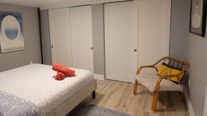 A bedroom with a bed, a chair, a wardrobe, and a framed picture on the wall.