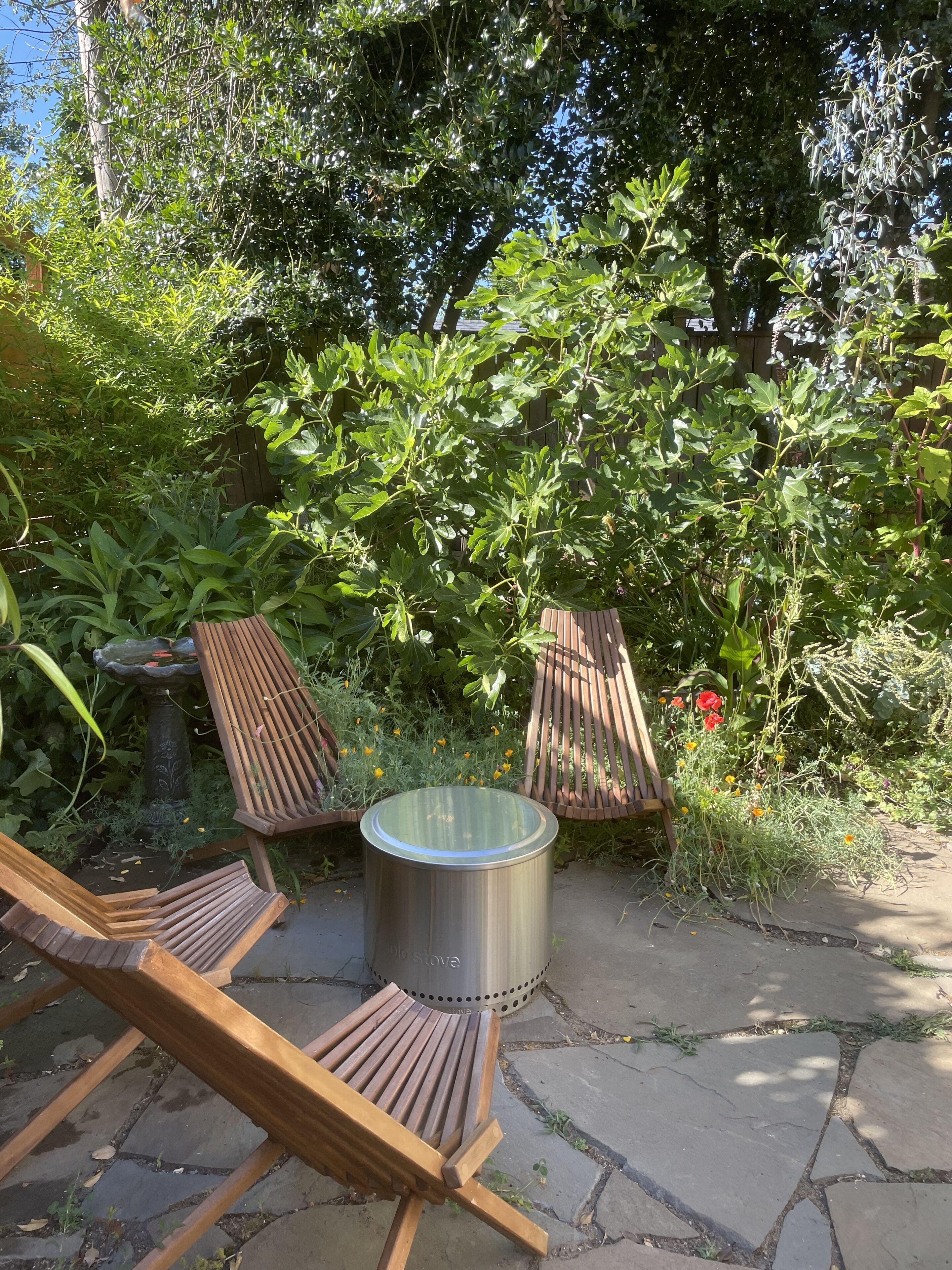 Un patio con dos sillones de madera y una mesa de metal.