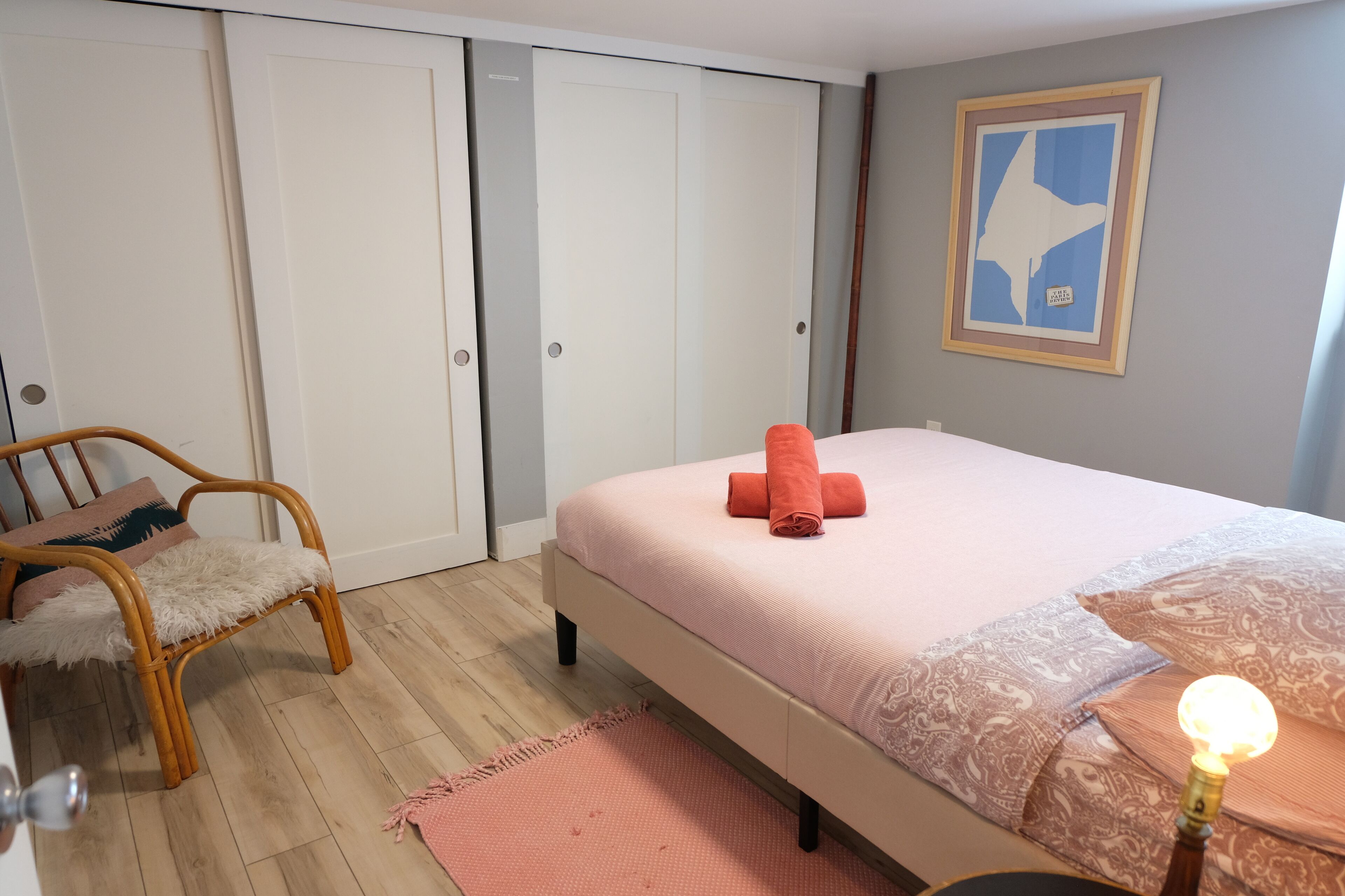 Une chambre à coucher comprenant un lit, une chaise, une table de chevet avec une lampe et une armoire.