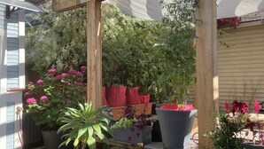 A wooden pergola structure with potted plants and flowers underneath.