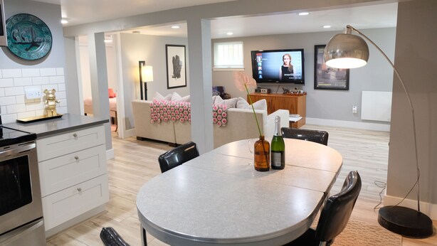 A modern kitchen with a dining area, a TV, and a large window.