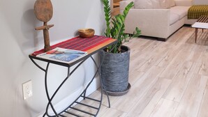 A living room with a sofa, a coffee table, a potted plant, and a wall-mounted mirror.