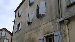 Un edificio con diverse finestre, alcune dotate di persiane, e una porta ben visibile.