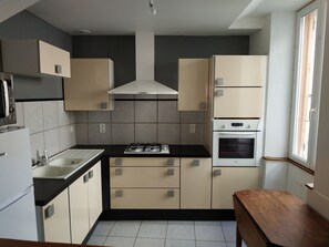 A modern kitchen with a gas stove, oven, and built-in microwave. There is a window providing natural light.