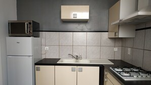 Una cucina con frigorifero, microonde, lavello e piano cottura a gas.