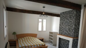 Una camera da letto con un letto, un comodino, una lampada, un camino e una finestra.