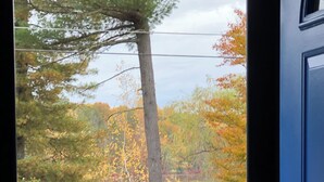 A wooden deck with a railing, overlooking a body of water and trees with autumn foliage.