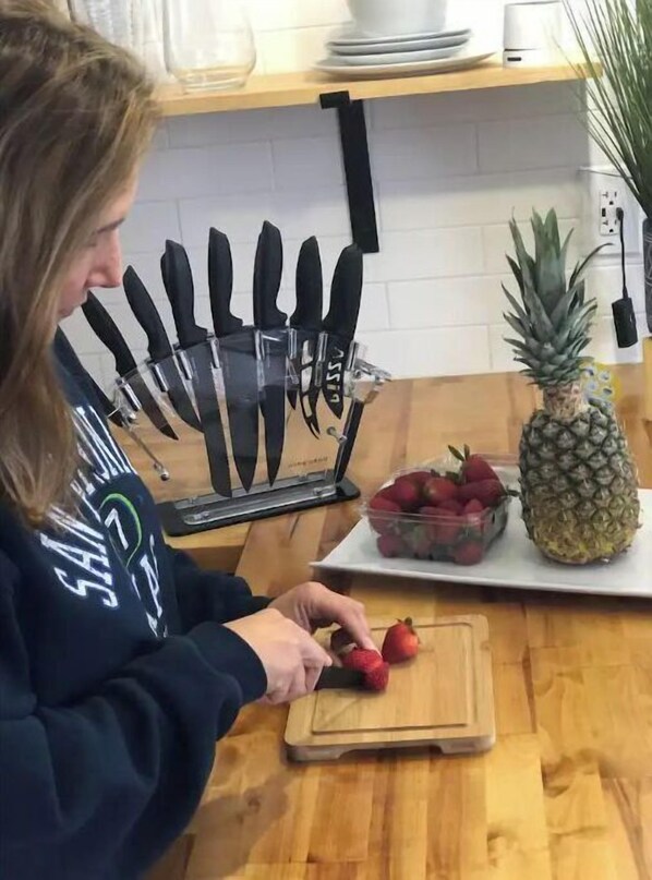 Un plan de travail de cuisine avec une planche à découper, un ananas et un saladier de fraises.