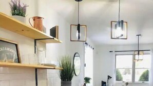 A modern kitchen with a wooden countertop, black cabinets, and pendant lights.