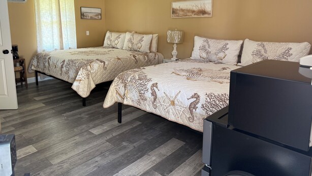 A bedroom with two beds, a coffee maker, a lamp, and a TV.