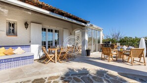 A patio with stone flooring, wooden furniture, and a white wall with blue trim. - Charming Provencal house with swimming pool (Bormes-les-Mimosas)