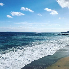 A beach with waves crashing onto the shore under a clear sky.
