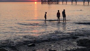 A sunset over a calm body of water with a pier extending into the water.