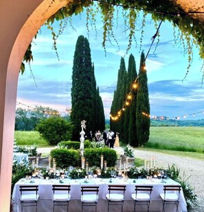 An outdoor dining area with a table set for a meal, surrounded by greenery and tall trees. - Splendid Chianti Tuscany Villa with Panoramic Pool ,Cypress Trees-Lined Drive (Montespertoli)