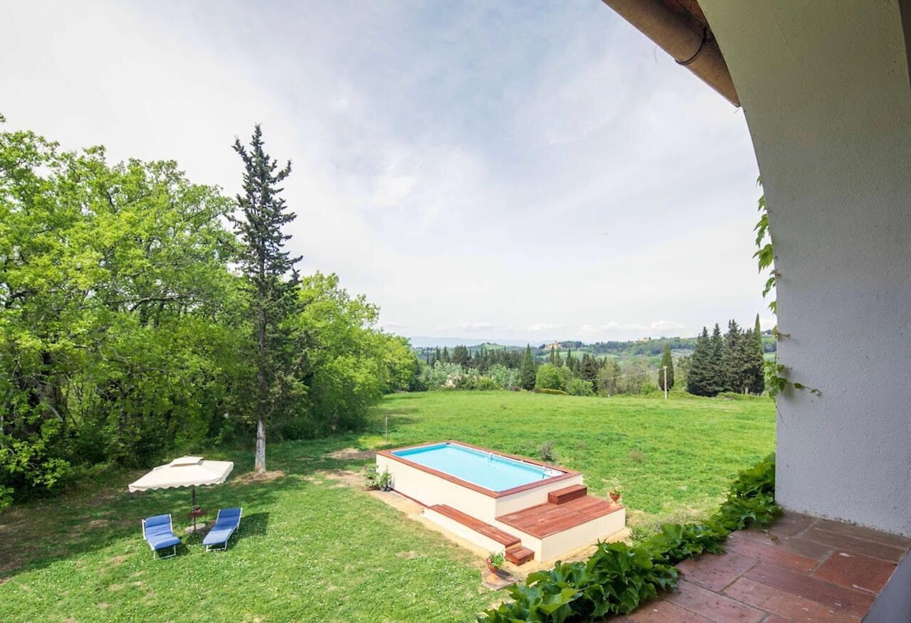 Un pati amb una piscina, dues gandules i vistes al camp.