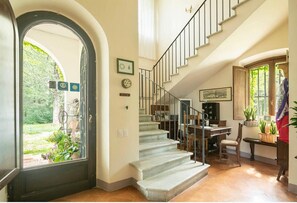 A staircase leading to a second floor, a dining area with a table and chairs, and a door with a view of the garden. - Splendid Chianti Tuscany Villa with Panoramic Pool ,Cypress Trees-Lined Drive (Montespertoli)