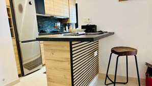 Une cuisine moderne avec un îlot central en bois, une cuisinière encastrée et un tabouret de bar.