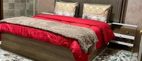 A bedroom with a bed, bedside tables, and a patterned rug.