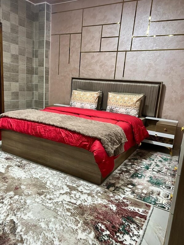 A bedroom with a bed, bedside tables, and a patterned rug.
