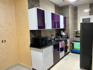 Una cocina con armarios blancos, encimera negra y estufa.