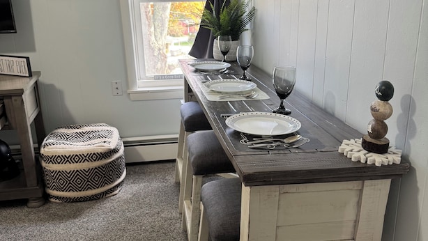 Un comedor con una mesa de madera rústica dispuesta para cuatro personas, una planta en maceta y un letrero que dice 'Father'.