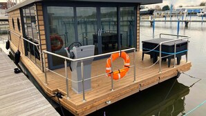 Ein hölzernes Boot mit einer gläsernen Kabine, Steuer und einem Rettungsring.