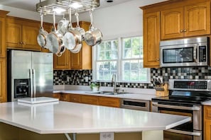 Enjoy cooking in this well-equipped kitchen with a central island, stainless steel appliances, and wooden cabinetry.