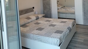 Une chambre moderne avec un grand lit, une porte en verre et un mur miroir.