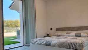 Une chambre à coucher avec un lit, une table de chevet, une fenêtre et une vue sur une pelouse verdoyante.