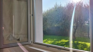 Une pièce dotée d’une grande fenêtre donnant sur un jardin verdoyant et des arbres.