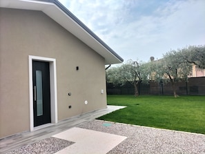Une maison moderne avec une façade beige, une porte noire et une pelouse bien entretenue.